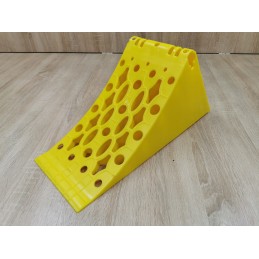 A chock under the wheel of a car trailer secures the large wheel