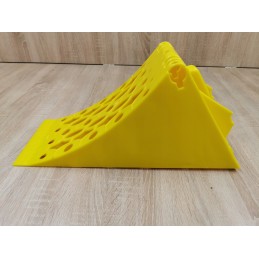 A chock under the wheel of a car trailer secures the large wheel