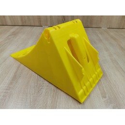 A chock under the wheel of a car trailer secures the large wheel