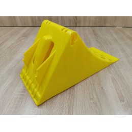 A chock under the wheel of a car trailer secures the large wheel