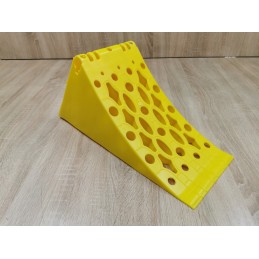 A chock under the wheel of a car trailer secures the large wheel